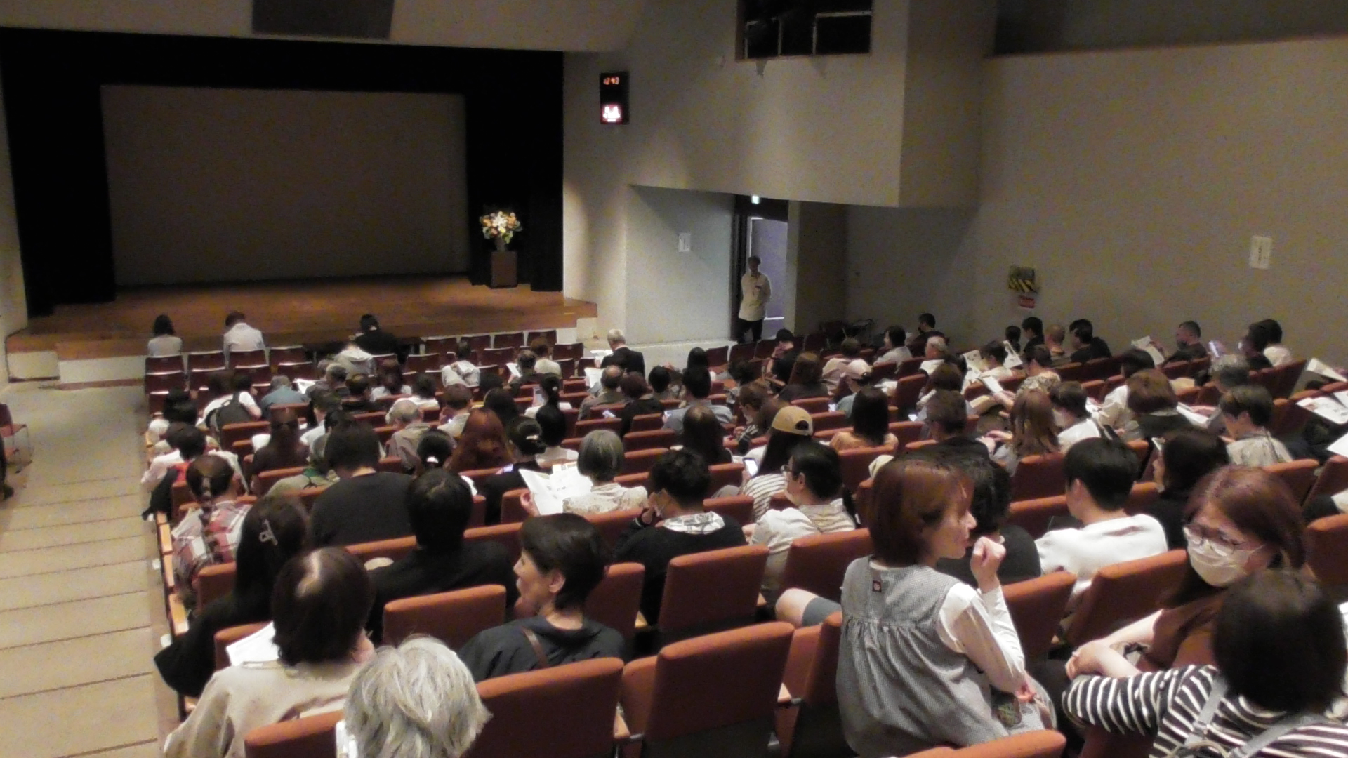 多くの来場者で埋まった会場で、映画の上映開始を楽しみにしている参加者たち。